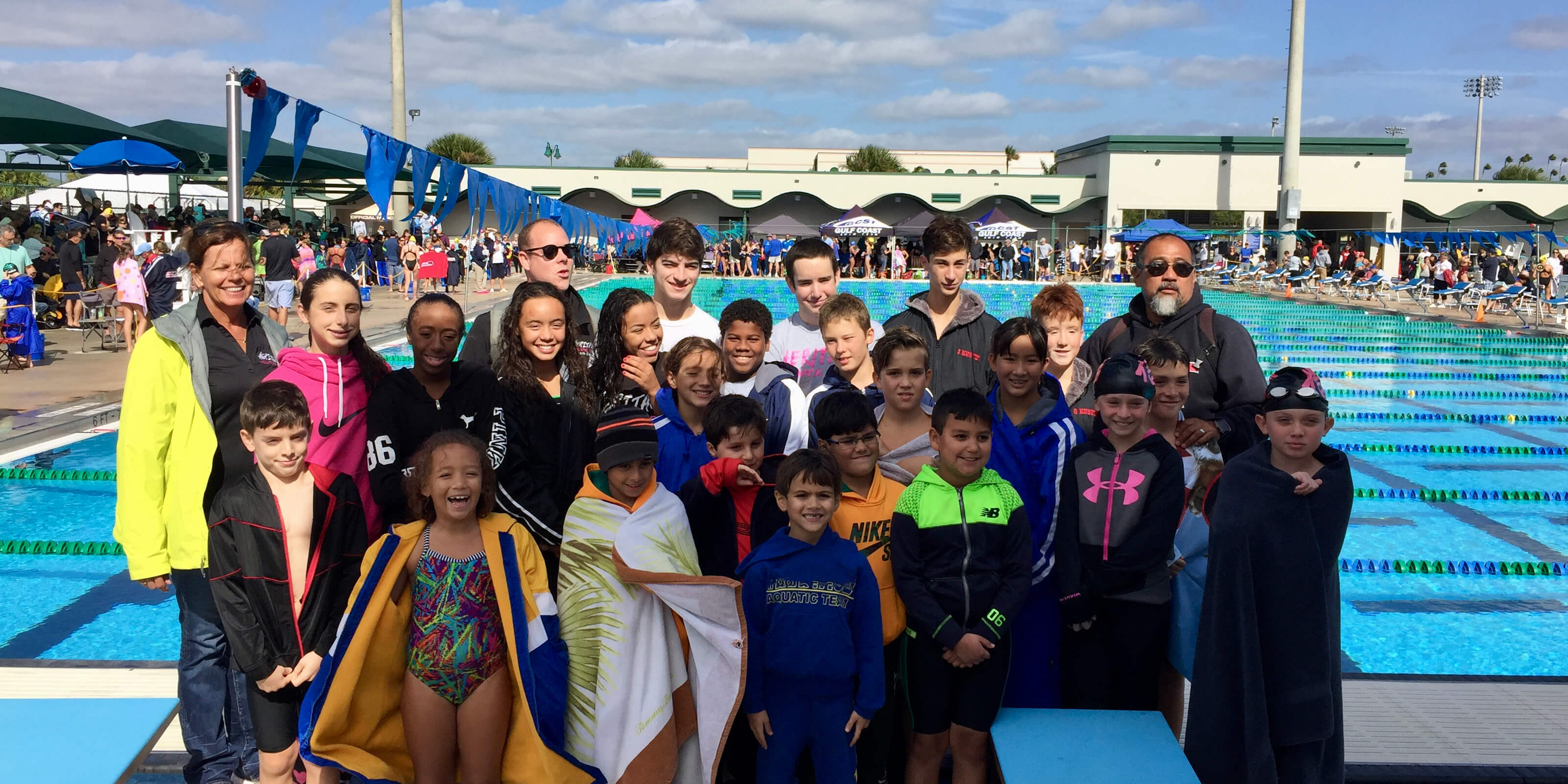 a group shot of a swim team in front of an olympic sized competitive swim pool