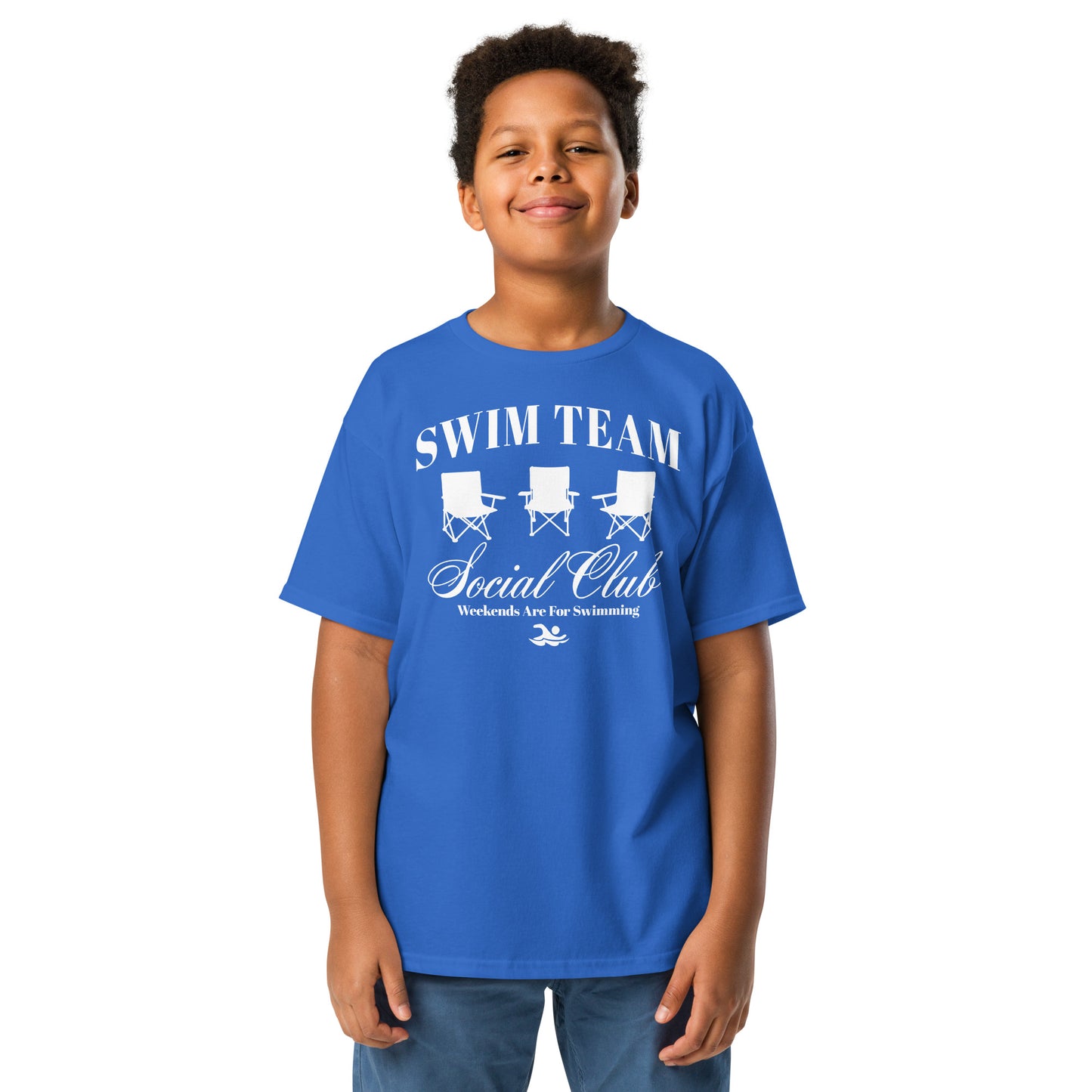 Boy wearing royal blue Swim Team Social Club Youth T-shirt by TrendySwimmer, featuring foldable chair graphic and swim lifestyle slogan.